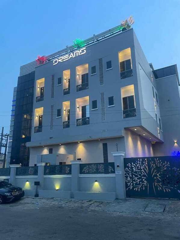 A modern building with the sign "Dreams" on the top. It has multiple floors with balconies and windows. - DREAMS BY DV8 (Lagos)