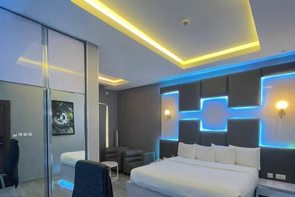 A modern bedroom with a large bed, a desk, and a chair.