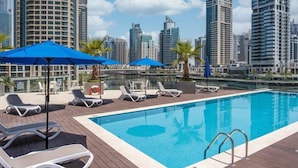 A rooftop pool with lounge chairs and umbrellas, surrounded by tall buildings and a body of water. - LIV Residence (Dubai)