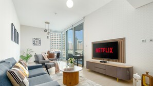 A modern living room with a grey sofa, a wooden coffee table, and a TV displaying "NETFLIX". - LIV Residence (Dubai)