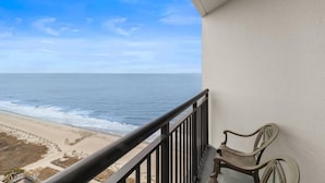 Un balcon avec vue sur l’océan, une chaise et une rambarde.