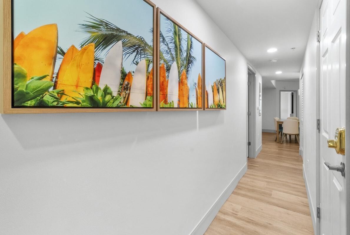 A hallway with a series of framed tropical artwork on the wall.