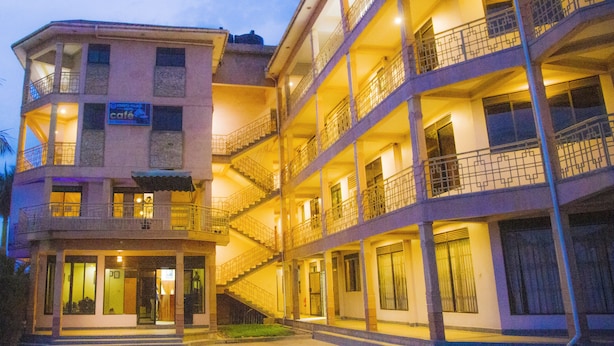Un hotel de varios pisos con balcones, una cafetería y una entrada bien iluminada.
