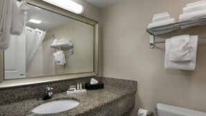 Een badkamer met een wastafel met granieten blad, een spiegel, een handdoekrek met opgevouwen handdoeken en een toilet.