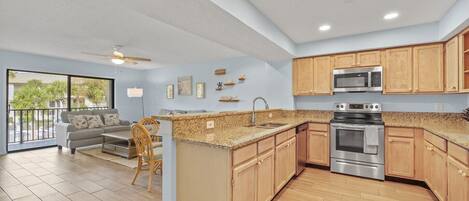 A spacious kitchen with wooden cabinets, a granite countertop, and stainless steel appliances.