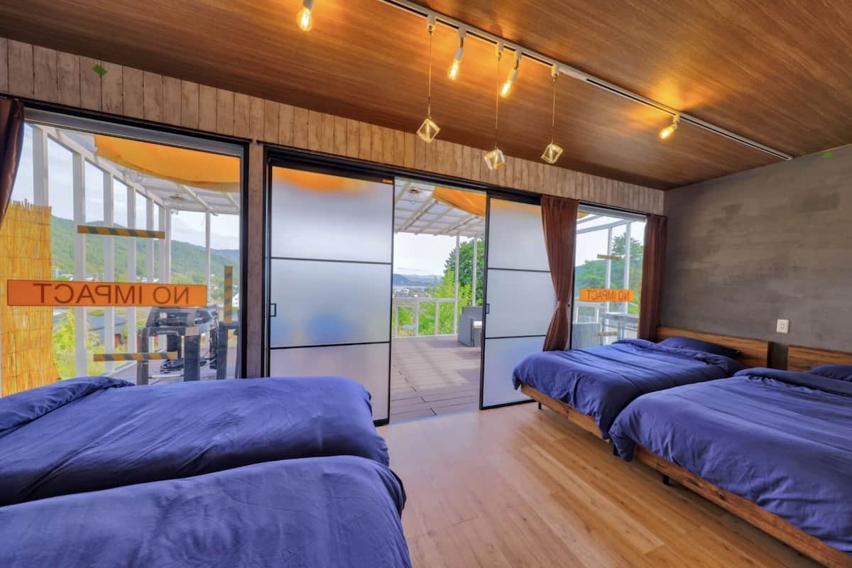 A modern hotel room with two beds, wooden flooring, and a balcony with a view.