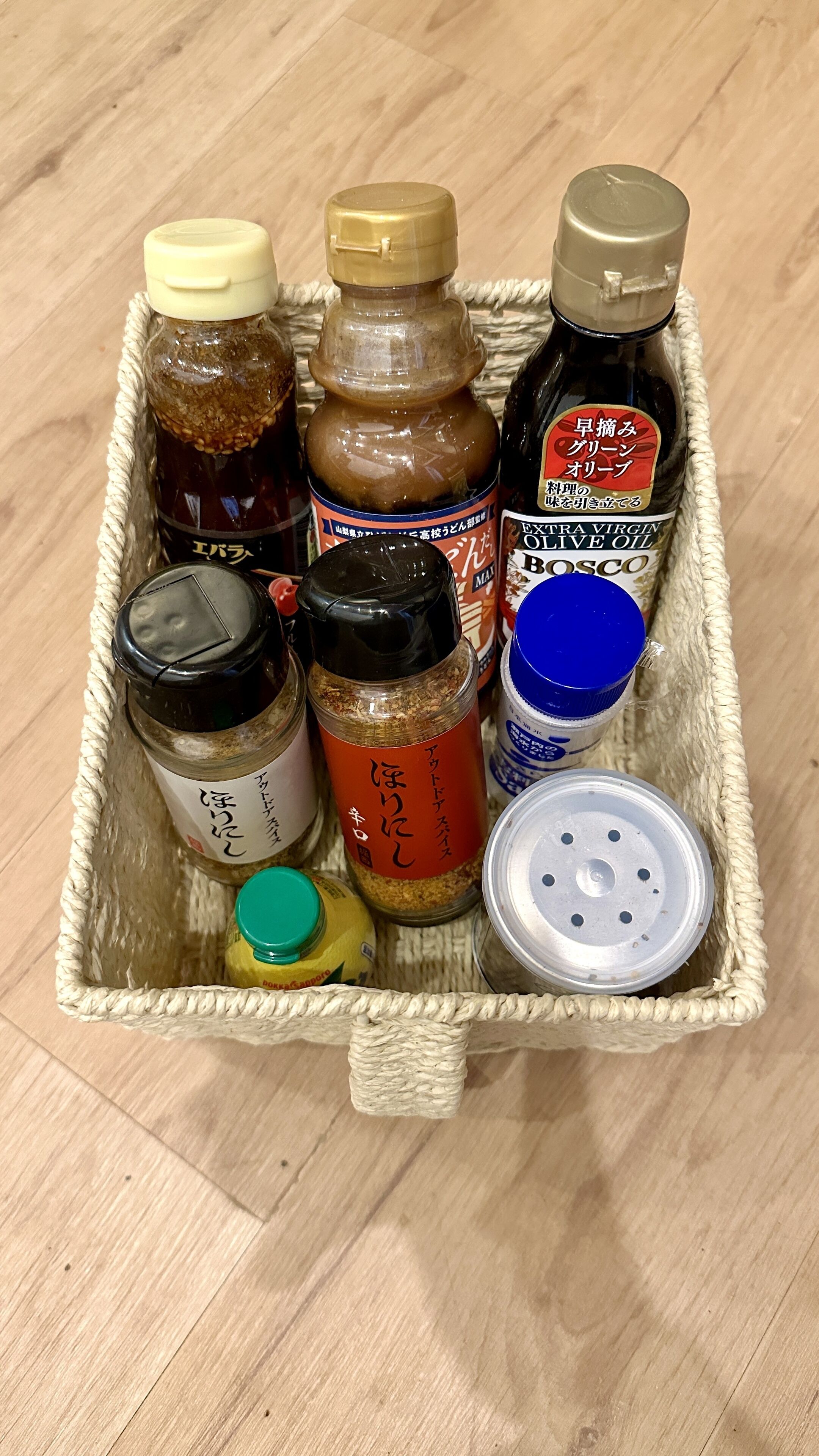 A woven basket containing various food items including jars of sauces and condiments.