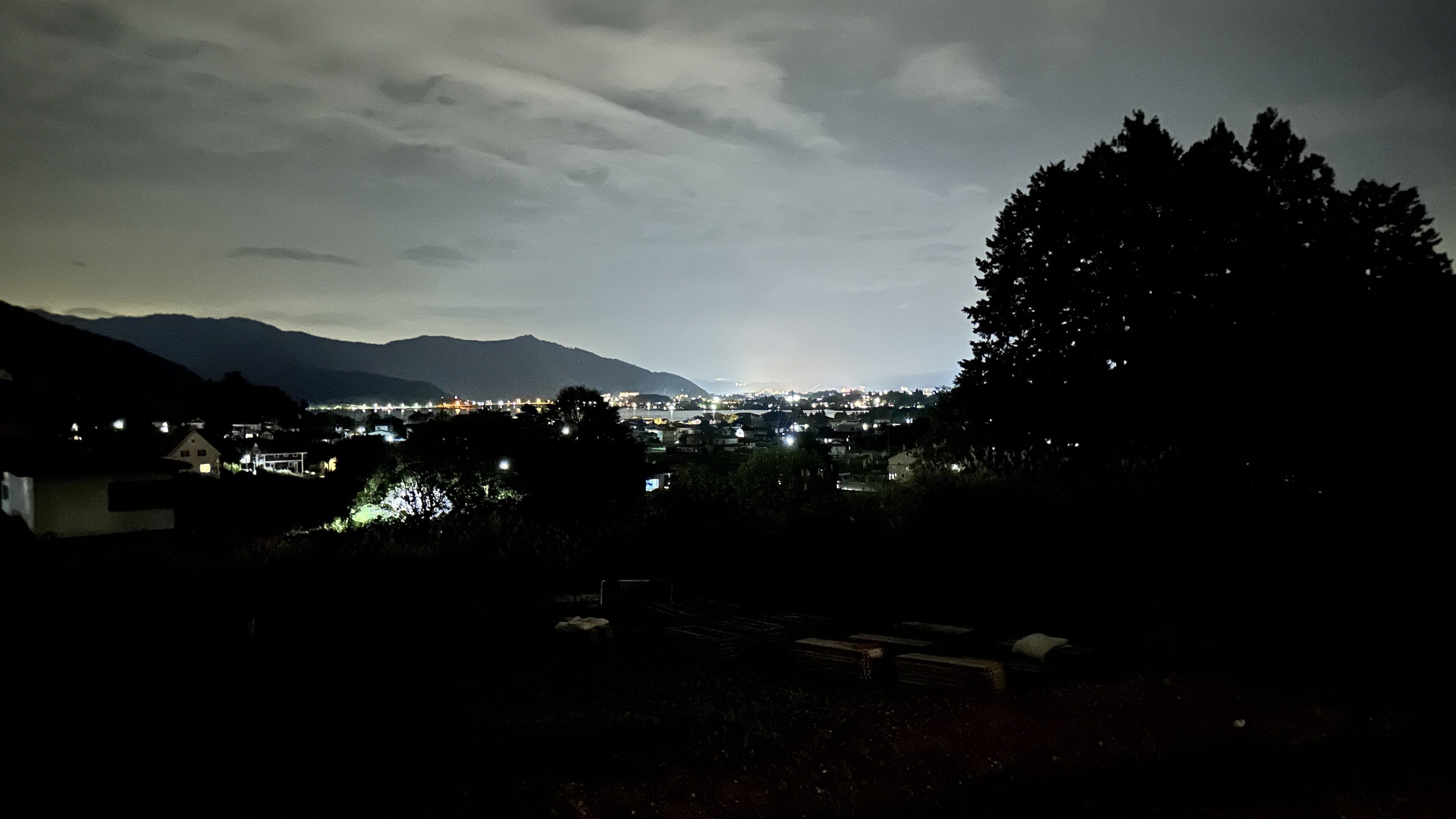 Ein Nachtblick auf eine Stadt mit Häusern und Bergen im Hintergrund.