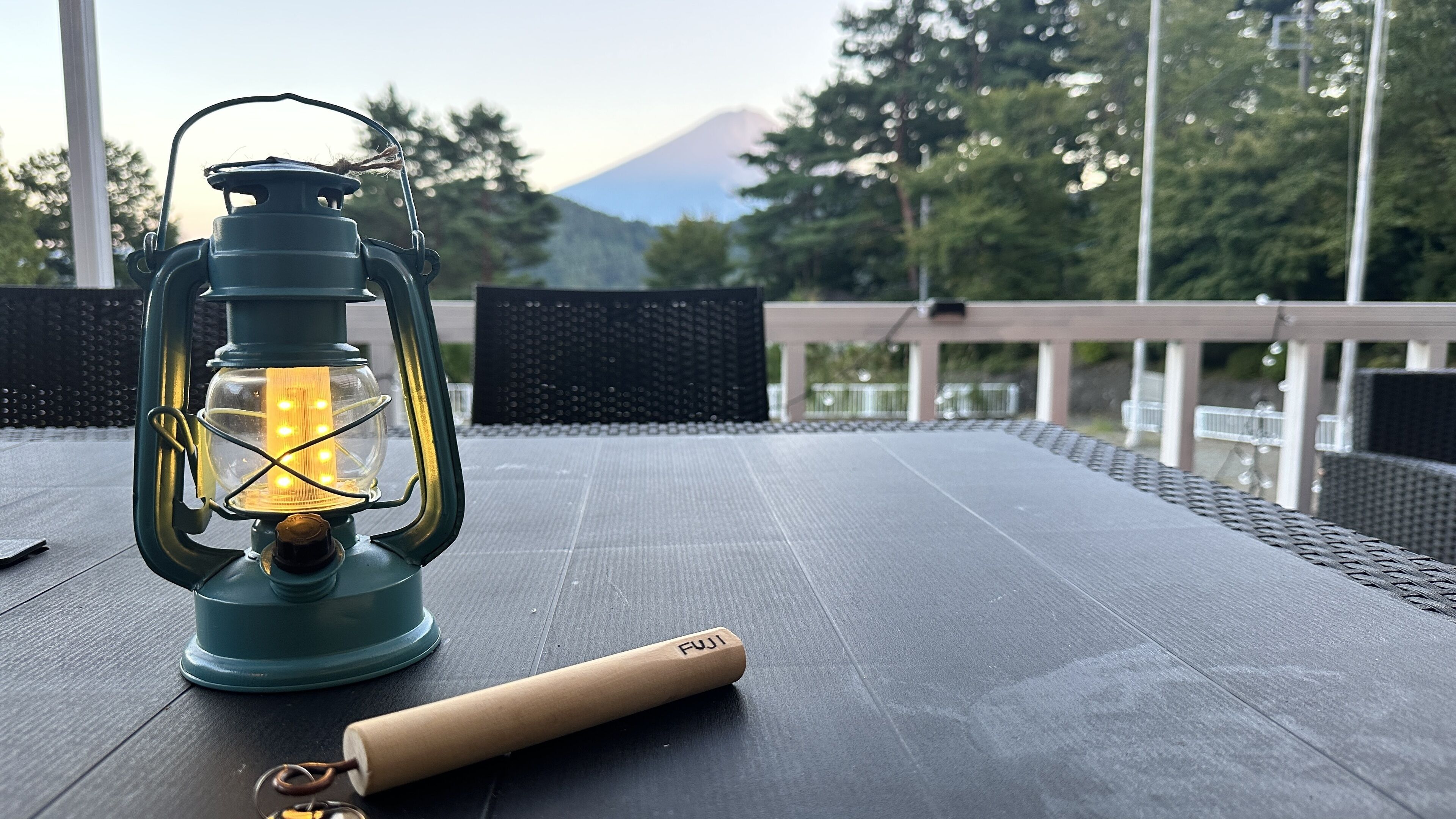 A lantern on a table with a view of a mountain in the background.