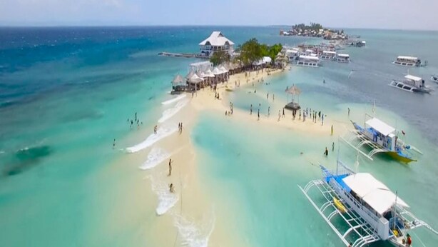 An aerial view of a beach resort with a pier, clear turquoise waters, and several boats. - Stunning and brandnew 1 BR corner unit for 5 Persons - woow ocean-views (Lapu-Lapu City)