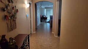 A hallway with a dining area on the left, a staircase, and a living room in the background. - Private putting green at Johnson Ranch 3 bedroom (San Tan Valley)