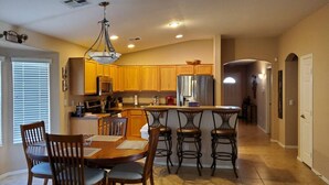 A spacious kitchen with wooden cabinets, a central island, and a dining area with chairs. - Private putting green at Johnson Ranch 3 bedroom (San Tan Valley)