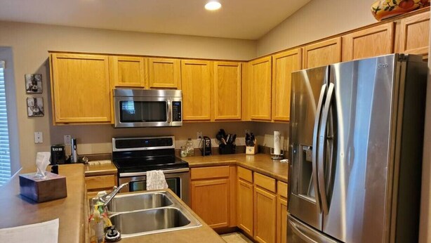 A modern kitchen with wooden cabinets, stainless steel appliances, and a built-in microwave. - Private putting green at Johnson Ranch 3 bedroom (San Tan Valley)