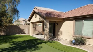 A residential property with a well-maintained lawn, a patio area, and a garage. - Private putting green at Johnson Ranch 3 bedroom (San Tan Valley)