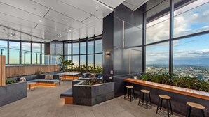 Ein stilvoller Lounge-Bereich mit Sitzgelegenheiten, einer Bar und großen Fenstern mit Blick auf die Stadt.