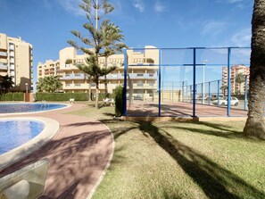 Et boligområde med swimmingpool, tennisbane og lejlighedskomplekser i baggrunden.