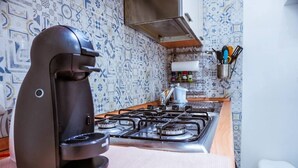 A kitchen with a gas stove, a coffee maker, and a patterned backsplash.
