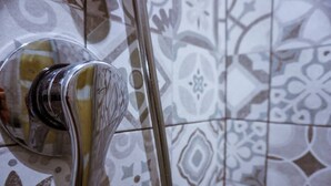 A bathroom with patterned tiles and a chrome faucet.