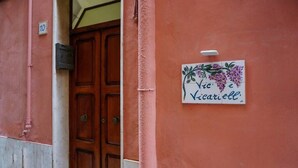 A building entrance with a wooden door, a sign with a floral design, and a number '10' on the wall.
