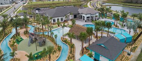 A resort with a swimming pool, palm trees, and a road.