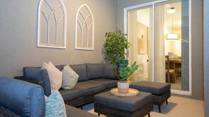 Una sala de estar moderna con un sofá gris, dos mesas auxiliares y una planta en maceta.