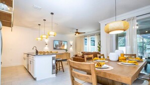 Una cocina moderna con una isla central, sillas de madera y una mesa de comedor lista para una comida.