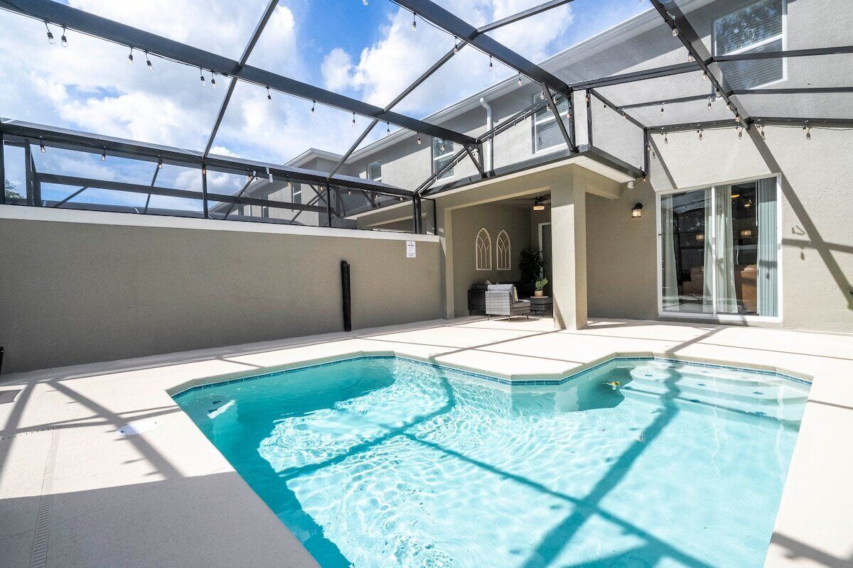 A rooftop swimming pool with a glass ceiling, a lounge area, and a view of the sky.