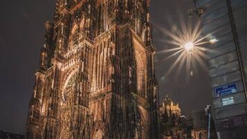 Een gotische kathedraal met ingewikkelde architectuur en een grote klokkentoren, verlicht in de nacht.