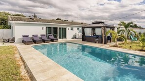 En swimmingpool med liggestole og et overdækket opholdsområde.
