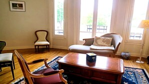 Una sala de estar con una mesa de centro de madera, un sillón rojo, un sofá gris y una alfombra estampada.