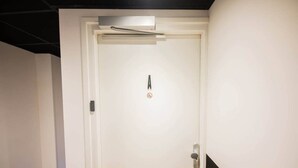 A white door with a security lock, a keyhole, and a small sign with a red circle and a line through it, indicating no entry. - Luxurious 35m² Designer Studio (R-51-A) (Eindhoven)