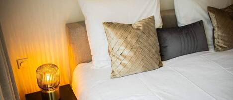 Een hotelkamer met een bed, een nachtkastje met een lamp en een wandlamp.