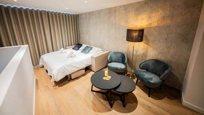 A modern hotel room with a bed, two chairs, a small table, and a floor lamp. - Historical City Retreat with Sauna option (R-51-B) (Eindhoven)