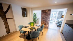 A dining area with a round table, four chairs, a potted plant, and a stone accent wall. - Historical City Retreat with Sauna option (R-51-B) (Eindhoven)
