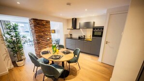 A modern kitchen with a built-in oven and a dining area with a round table and chairs. - Historical City Retreat with Sauna option (R-51-B) (Eindhoven)