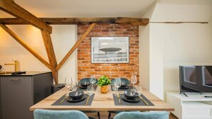 A dining area with a brick wall, a framed picture, and a TV on a stand. - Spectacular 70m² Penthouse with Terrace (R-51-C) (Eindhoven)