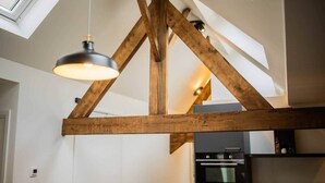 A kitchen with exposed wooden beams, a pendant light, and modern appliances. - Spectacular 70m² Penthouse with Terrace (R-51-C) (Eindhoven)