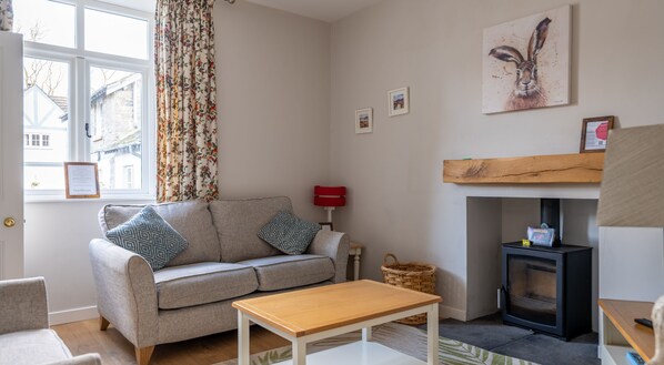 Un salon chaleureux avec un canapé, une table basse en bois, une cheminée et une fenêtre avec des rideaux.