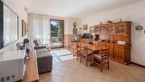 Ampla sala de estar com mesa de jantar, sofá e cozinha com armários de madeira.