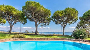 Piscina com vista clara para o mar e árvores ao fundo.
