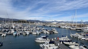 A marina with numerous boats docked, a clear sky, and mountains in the background. - (058) Le petit National (Antibes)