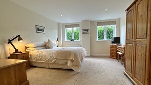 Een slaapkamer met een bed, nachtkastjes, een bureau, een televisie en een kledingkast.