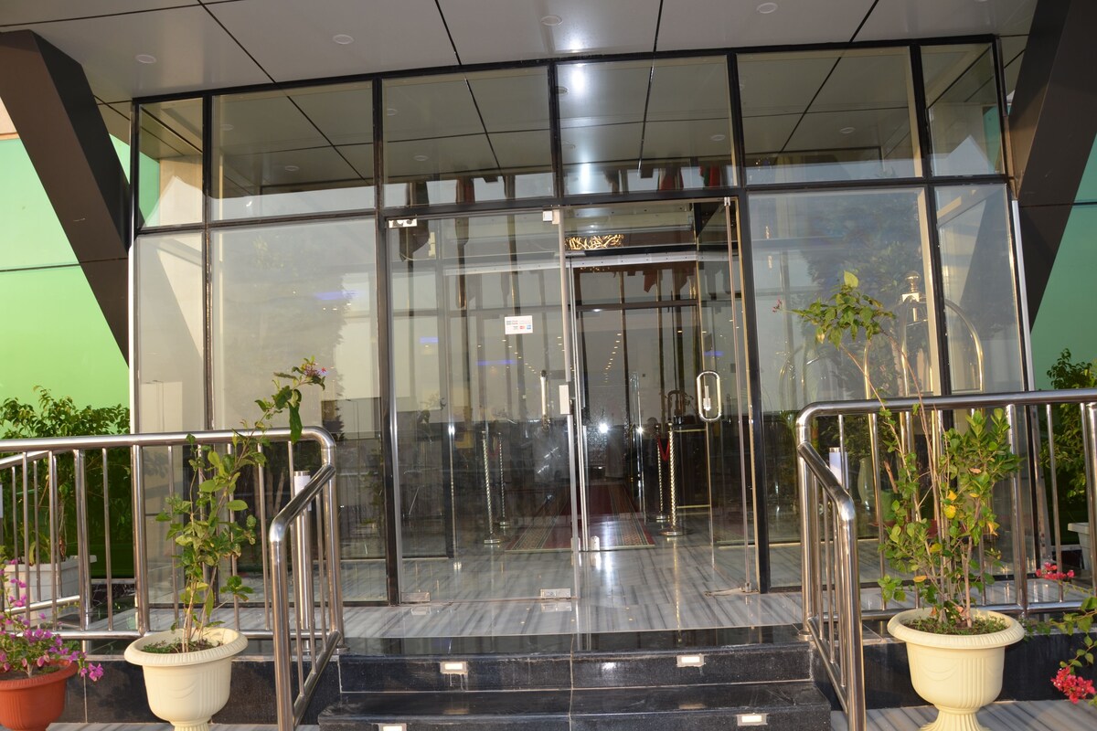 A hotel entrance with a glass door, metal railings, and potted plants.