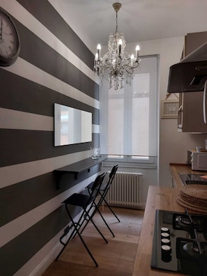 Una cucina con pareti a righe, un lampadario, un orologio e un fornello.