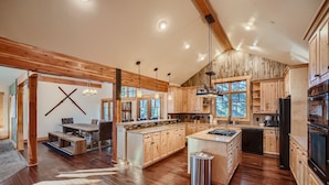 Une cuisine spacieuse avec des meubles en bois, un grand îlot central et un coin repas équipé d’une banquette.