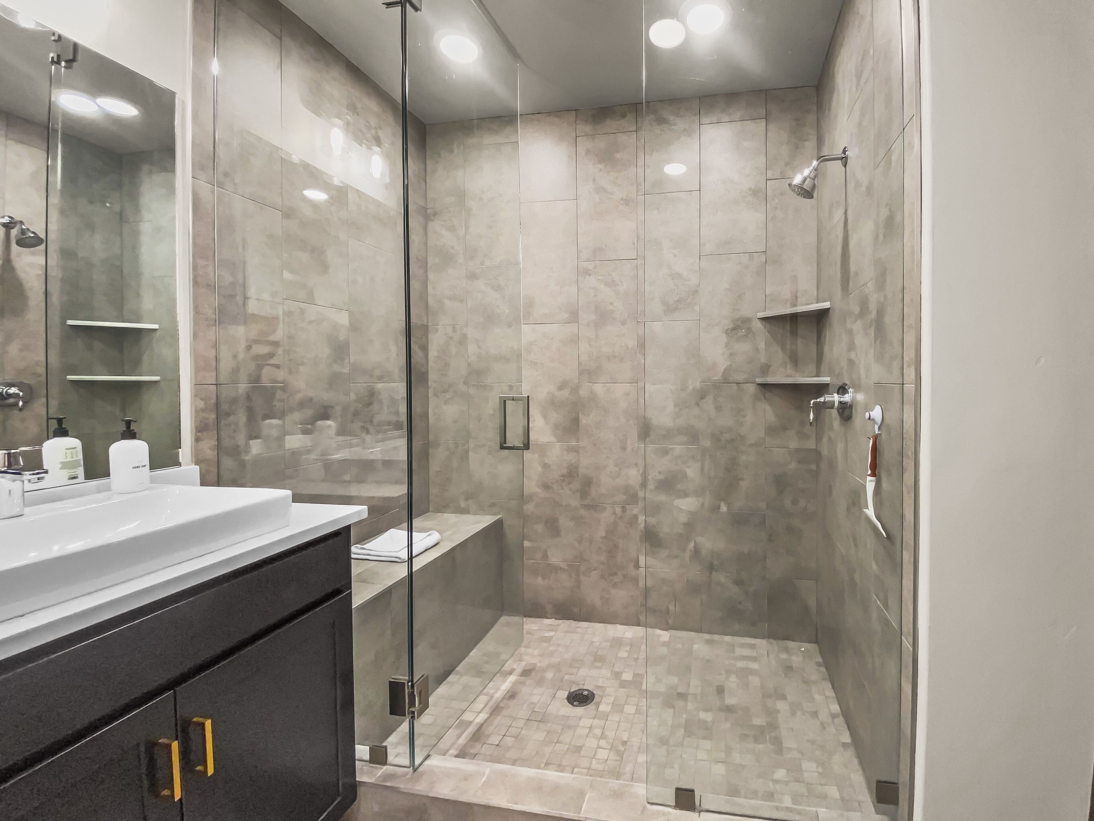 Un bagno moderno con doccia vetrata, un mobile vanitario con specchio e un lavandino.