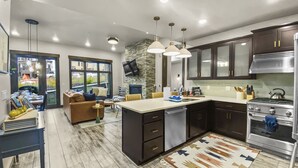 A modern kitchen with dark cabinets, stainless steel appliances, and a large island. - 106 Blackstone Mountain Marvel! 2 Bedroom Condo by RedAwning (Park City)