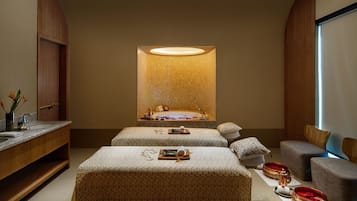 Relax in a serene spa room with a large mirror, central sink, and cushioned benches.