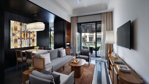 Una habitación de hotel moderna con sofá, sillas, una mesa de comedor, televisor y un ventanal con vistas.