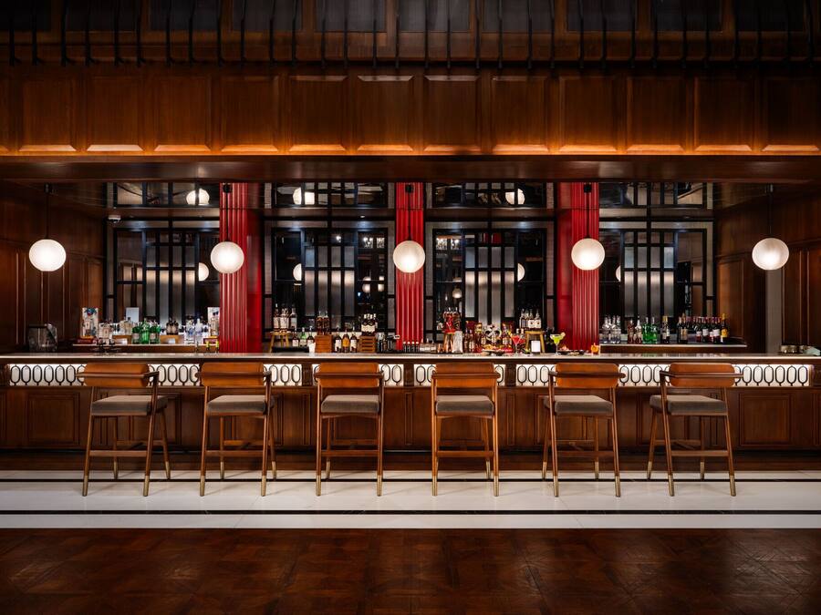 A bar area with wooden bar counters, bar stools, and hanging spherical lights.